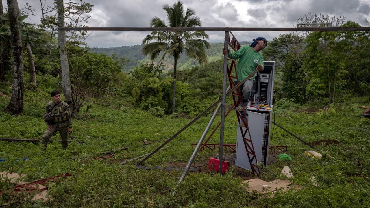 Contractors install a water pump as soldiers secure the area, in Padas, the Philippines.