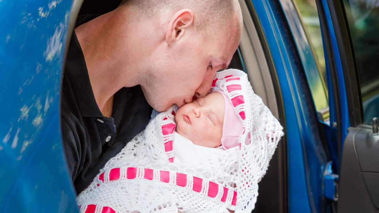 Father kisses newborn in car