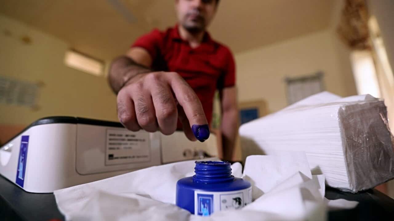An Iraq man inks his finger after casting his ballot