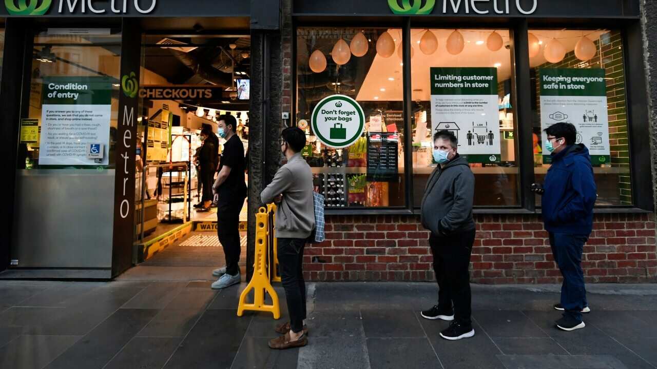 Customers line up at a supermarket before curfews begin