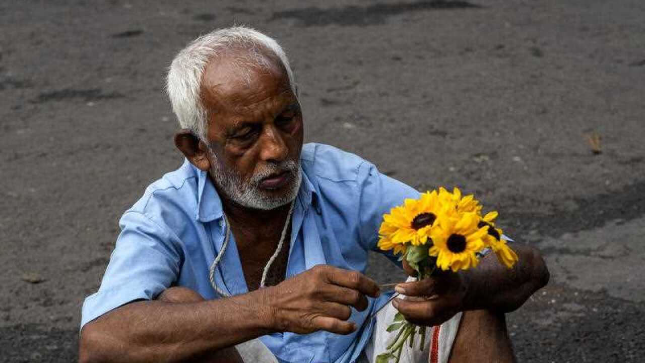 An elderly flower vendor makes a bunch of flowers at a market early morning in Kolkata, India, Sunday, May 29, 2022.