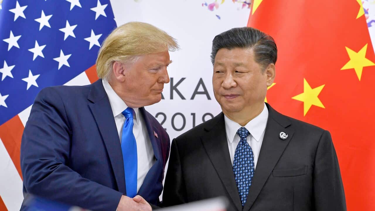 US President Donald Trump and Chinese President Xi Jinping shaking hands in front of the US and Chinese flags.