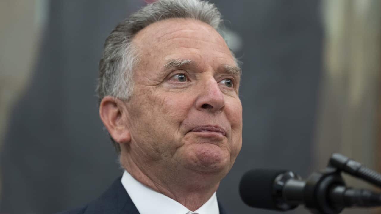 Man with greying hair speaking at microphone.