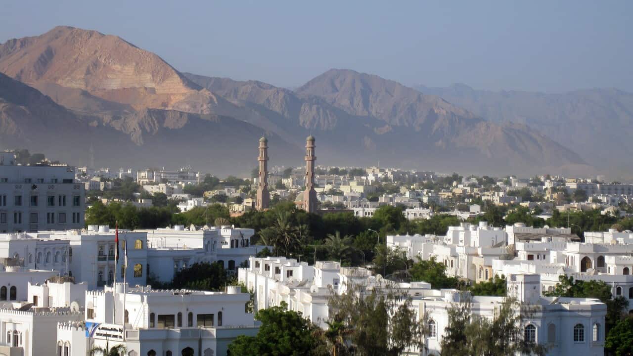 Omani capital of Muscat with mosque minarets visible and mountains in the background.