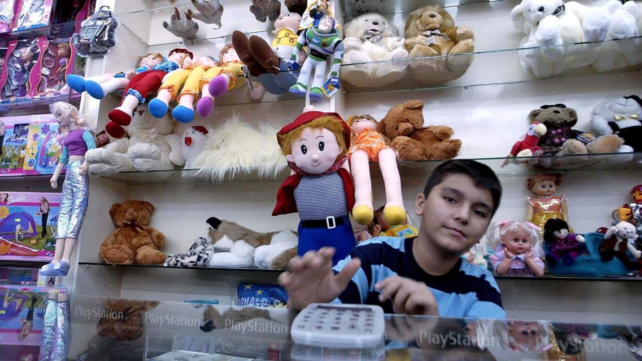 A boy sits in front of a row of toys in a shop