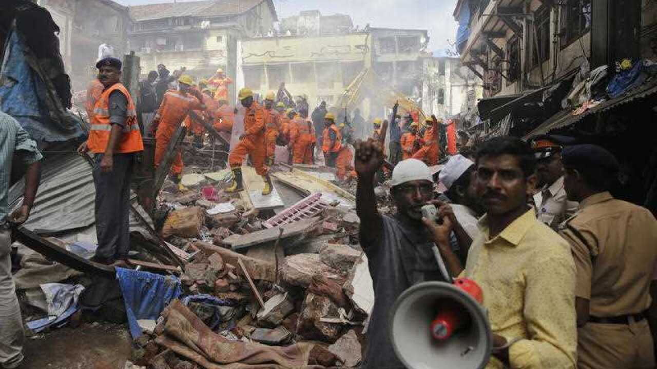  A rescue worker makes an announcement on a loudspeaker at the site of a building collapse in Mumbai, India, Thursday, Aug. 31, 2017. 