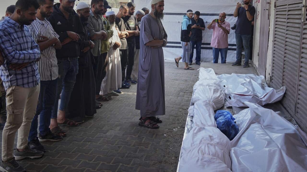 Palestinians pray over the bodies of 10 people killed in an Israeli strike while waiting to receive nutritional supplements at a clinic in Deir al-Balah (AAP)