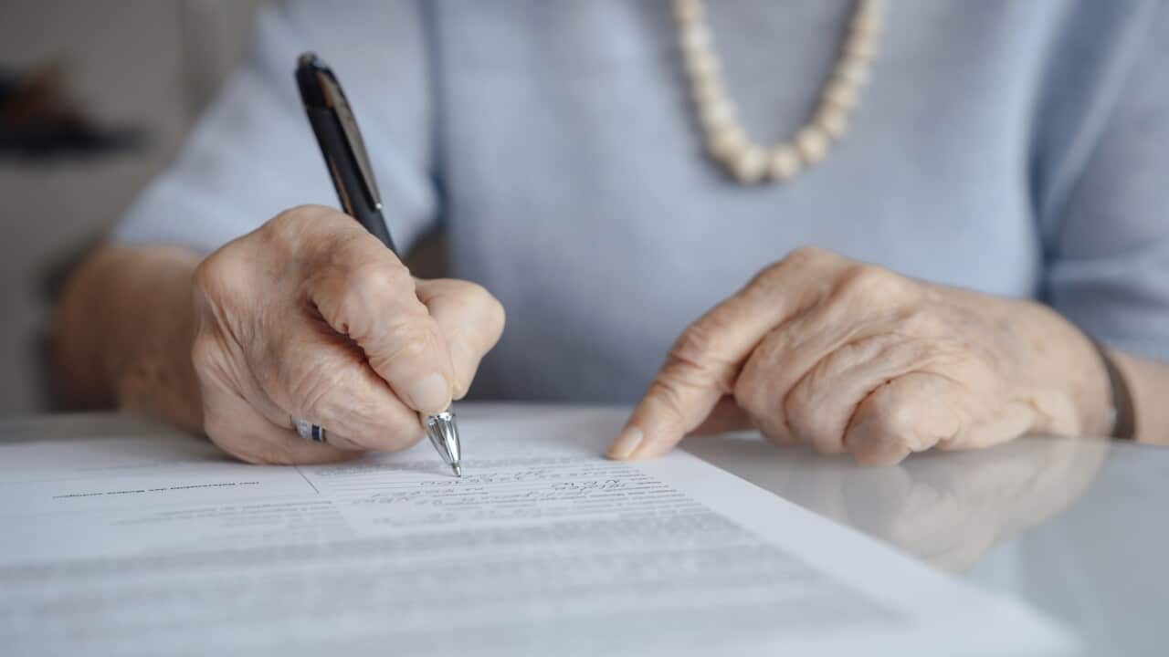 Hands of senior woman writing on paper with pen