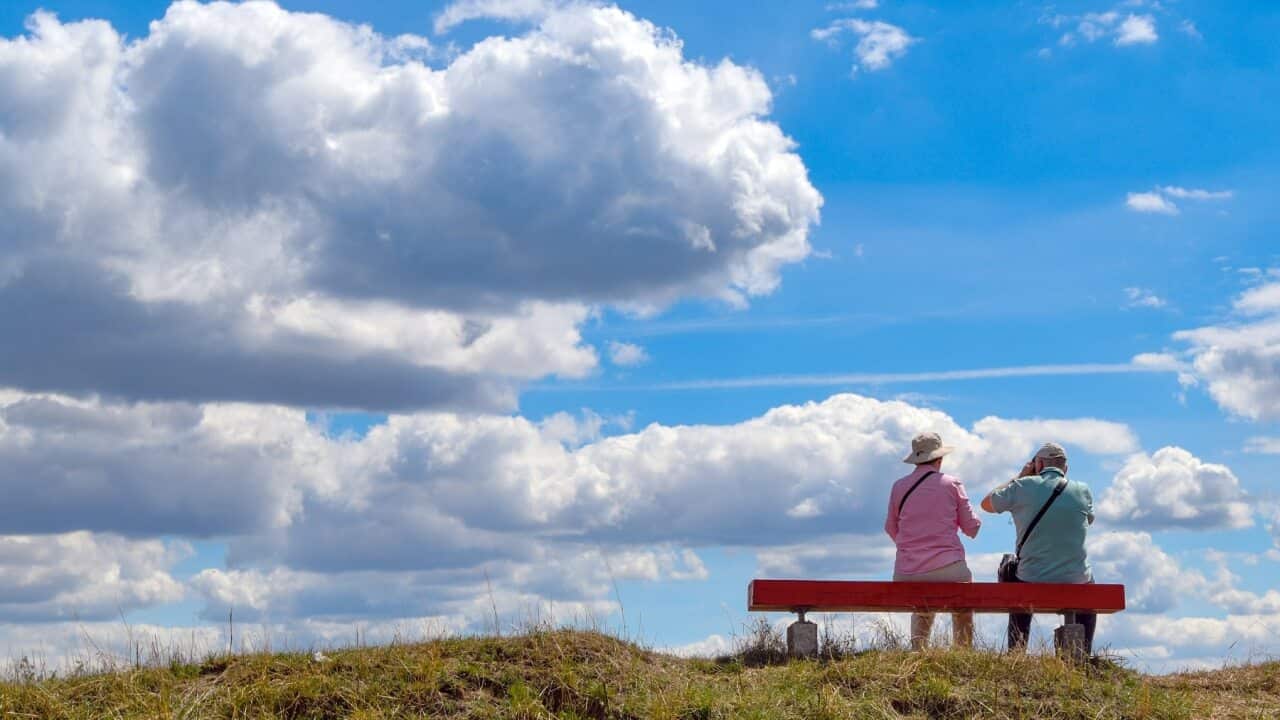 Two people sitting on a hilltop bench