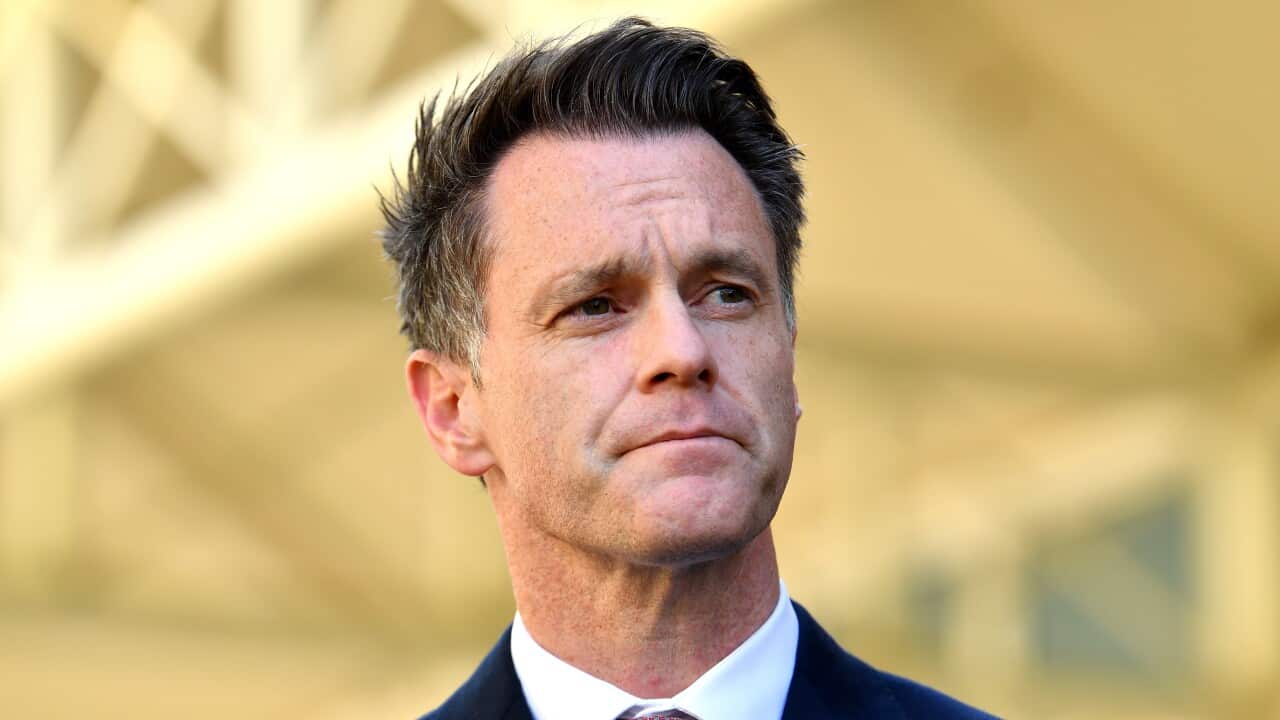 Chris Minns in a white shirt blue suit and pink tie underneath a bridge.