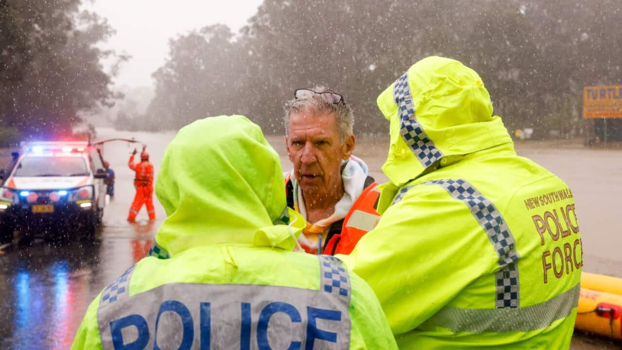 A man talks to police after he was rescued from his submerged car by State Emergency Service workers in Windsor NSW 