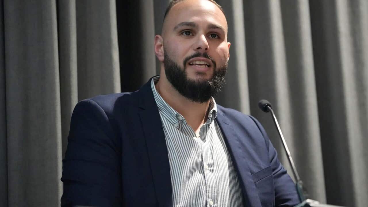 A man in navy suit speaking at a lectern.