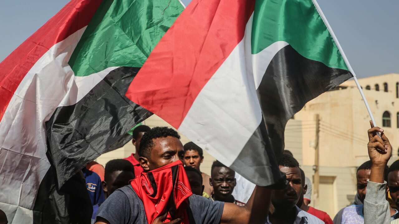 Sudanese protesters hold the national flag and chant during a demonstration in the capital Khartoum, 25 October 2021