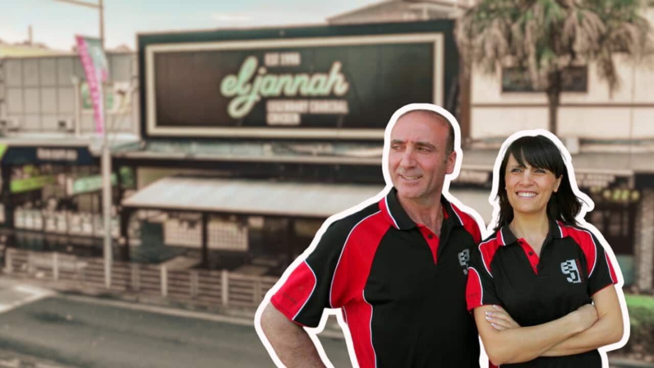 Two people in branded uniforms standing in front of an El Jannah restaurant.