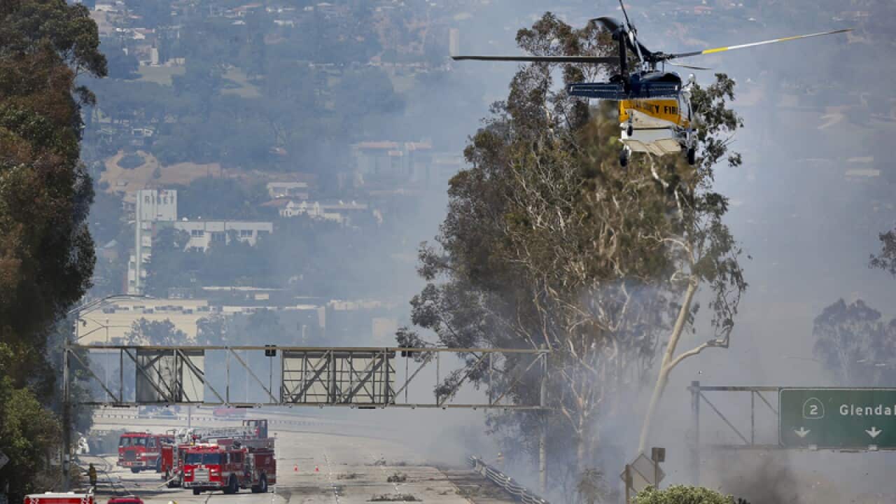 Firefighters use a helicopter to douse a fire, California