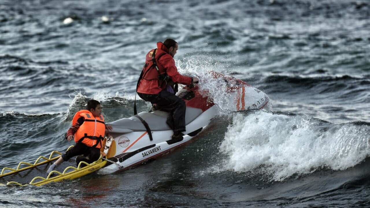 A Spanish lifeguard rescues a boy as a boat with refugees and migrants sunk on October 30, 2015, while crossing the Aegean sea from Turkey to reach the Greek island of Lesbos.