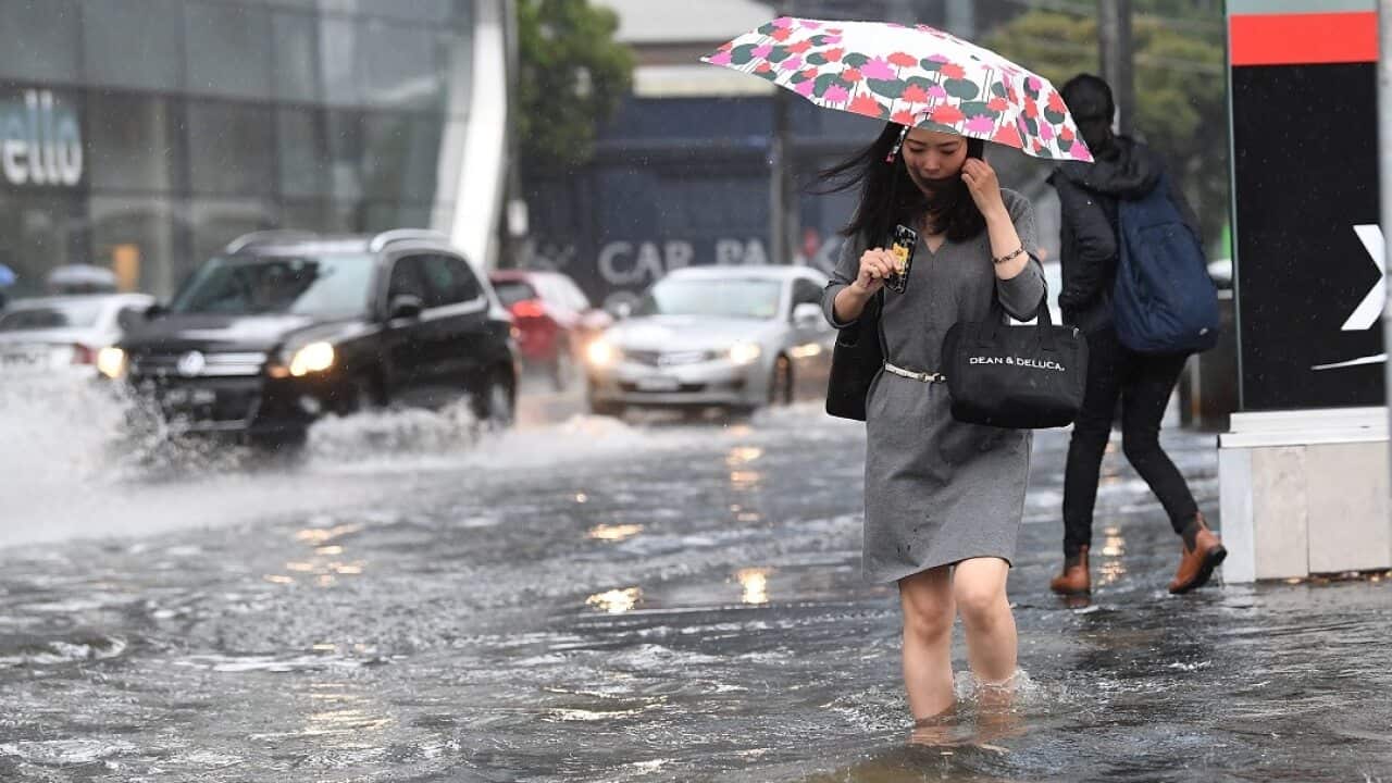 Pedestrians walk through flood waters.