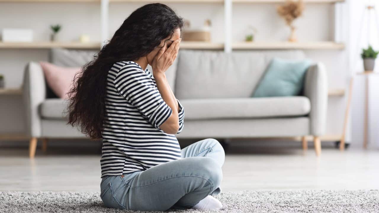 Crying pregnant woman feeling down while staying alone at home