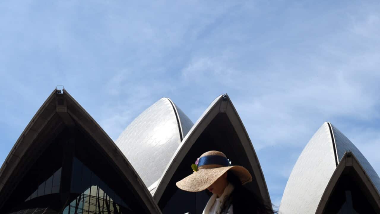 A tourist walks past the Sydney Opera House