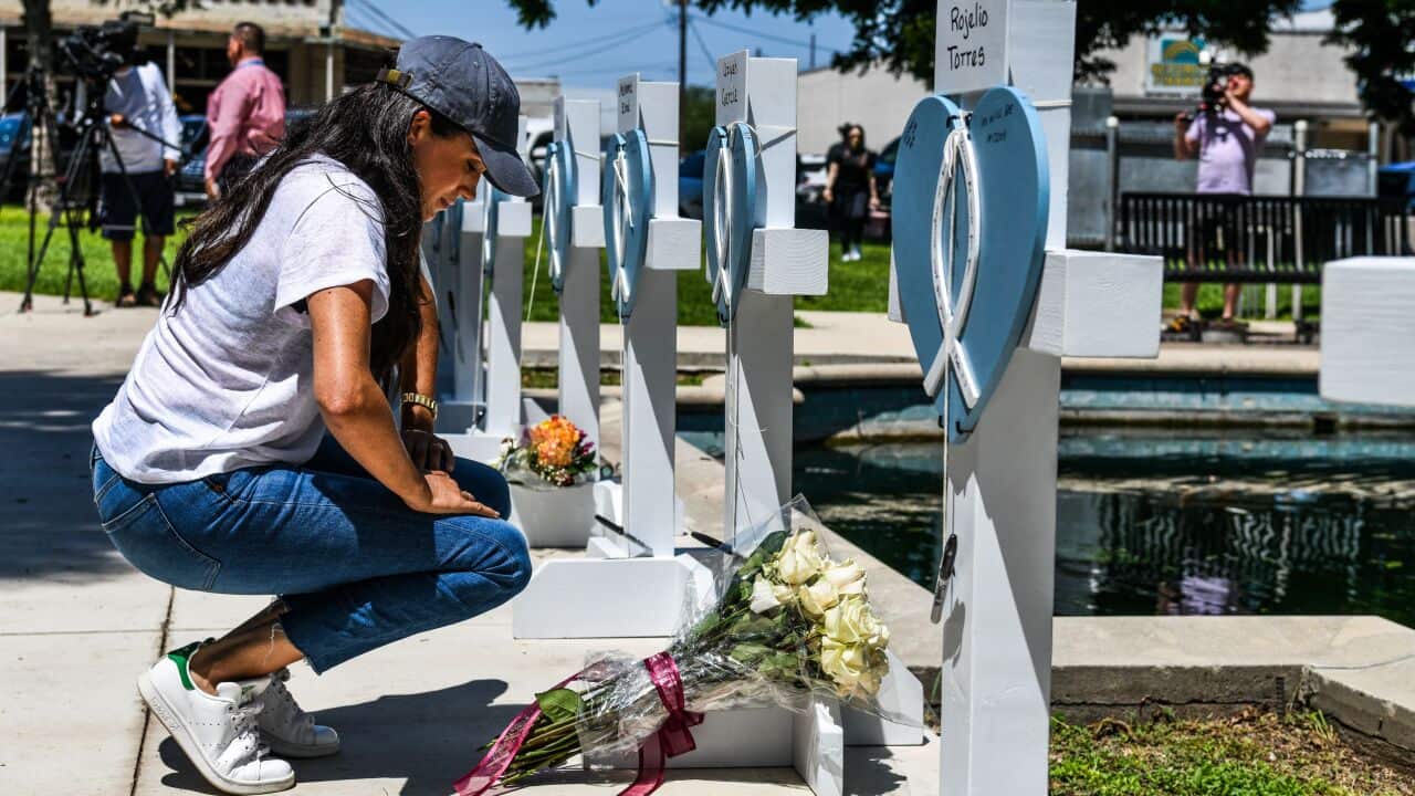 A woman seen kneeling in front of a memorial.