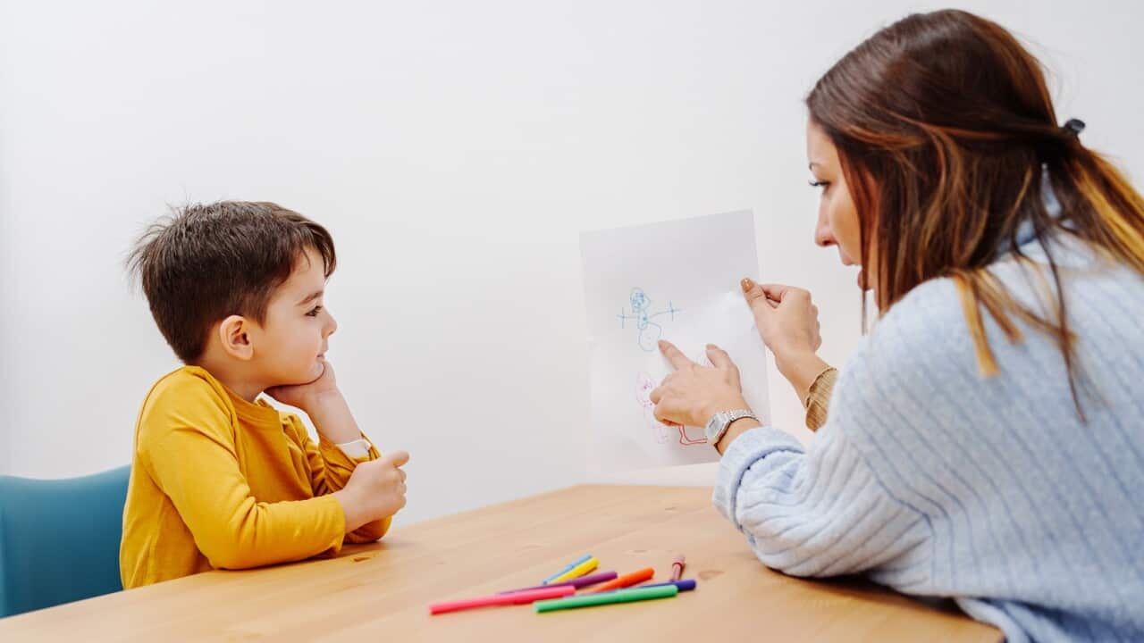 Psychology exercise for children, kid drawing family together with young educational therapist