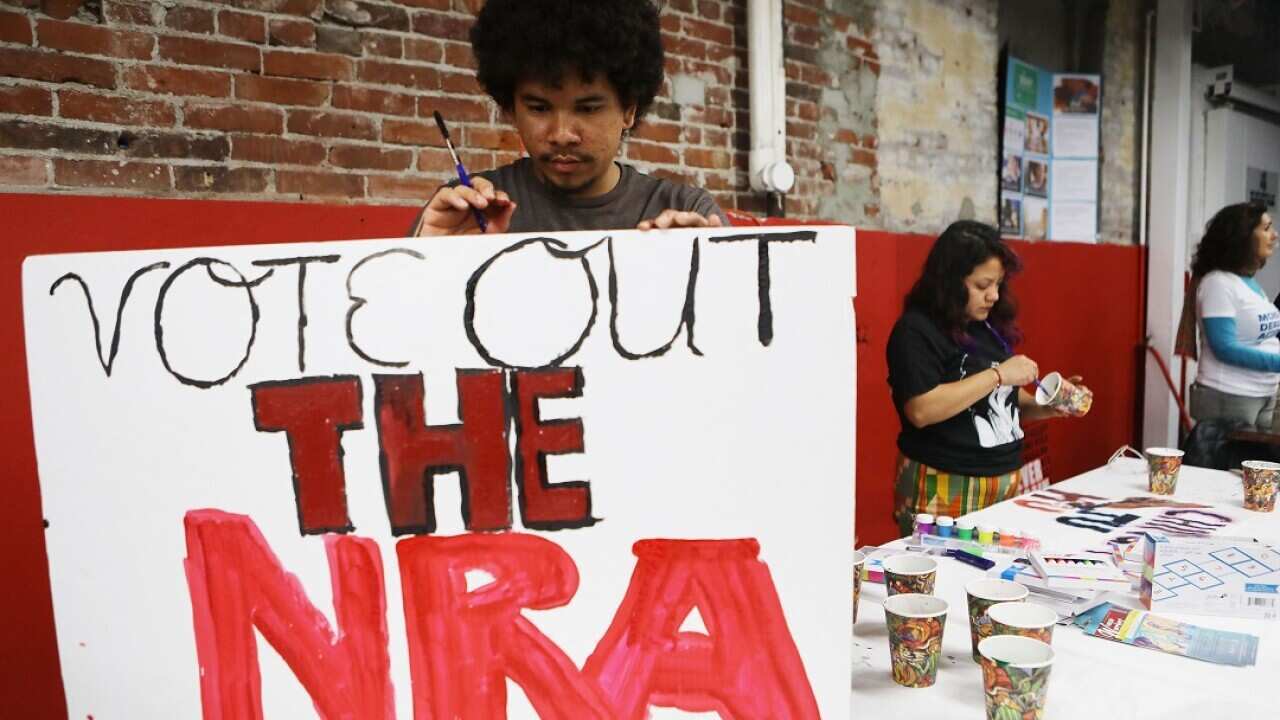 Activist and poet Johnny Soto paints a sign to be carried at the March for Our Lives rally as thousands are expected to take part across the US.
