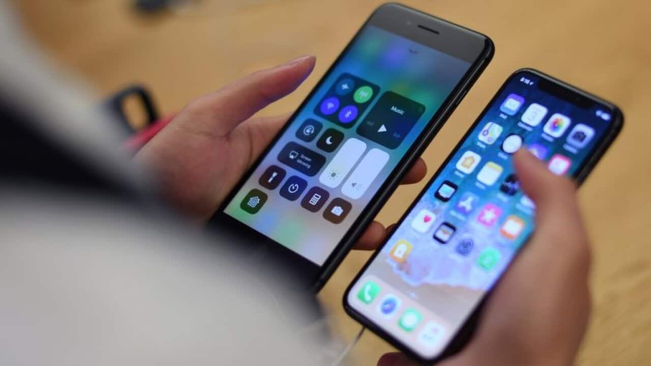 A man holds an iPhone X (right) while comparing it to an older model of iPhone, after the iPhone X's worldwide release to the general public, inside the Apple Store in Sydney, Friday, November 3, 2017. (AAP Image/David Moir) NO ARCHIVING