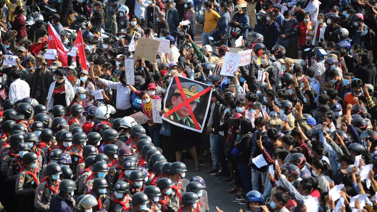 Protesters flashing three fingered salutes and holding an image with an X mark on the face of Myanmar Commander-in-Chief Senior General Min Aung Hlaing face rows of riot police in Naypyitaw, Myanmar