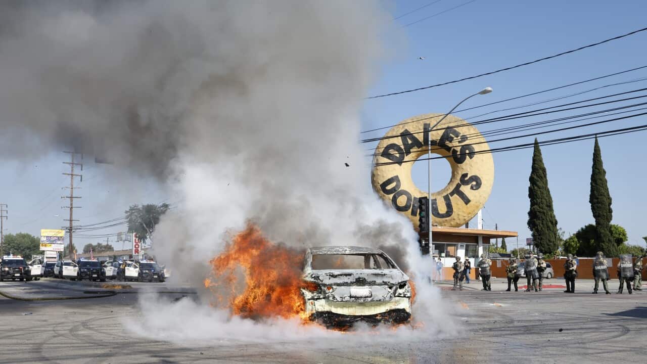 A car burns in the middle of the intersection of Atlantic Ave. and E Alondra Blvd. during ICE protests on Saturday, June 7, 2025 in Los Angeles, CA.