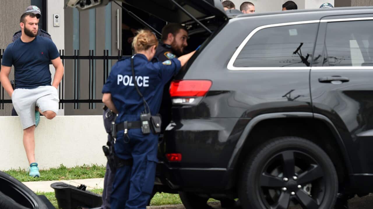 Police officers search a vehicle parked outside of a Sydney property