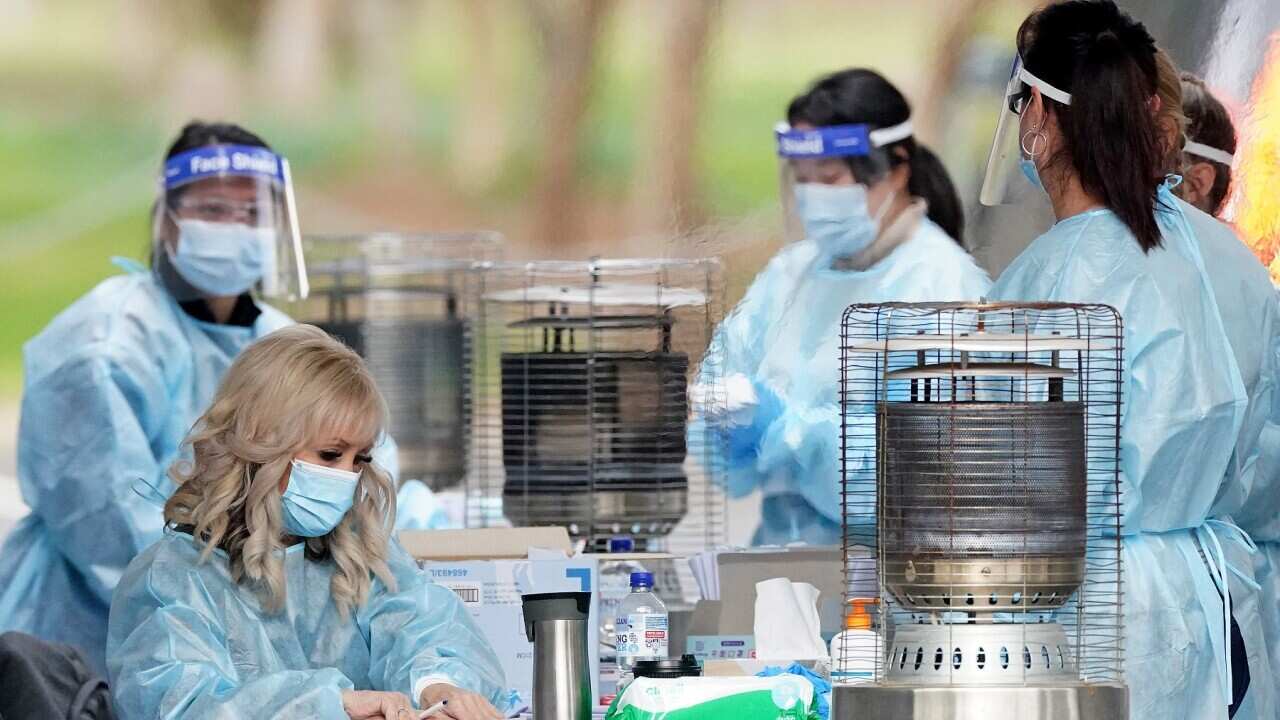 Medical workers look on before taking a sample