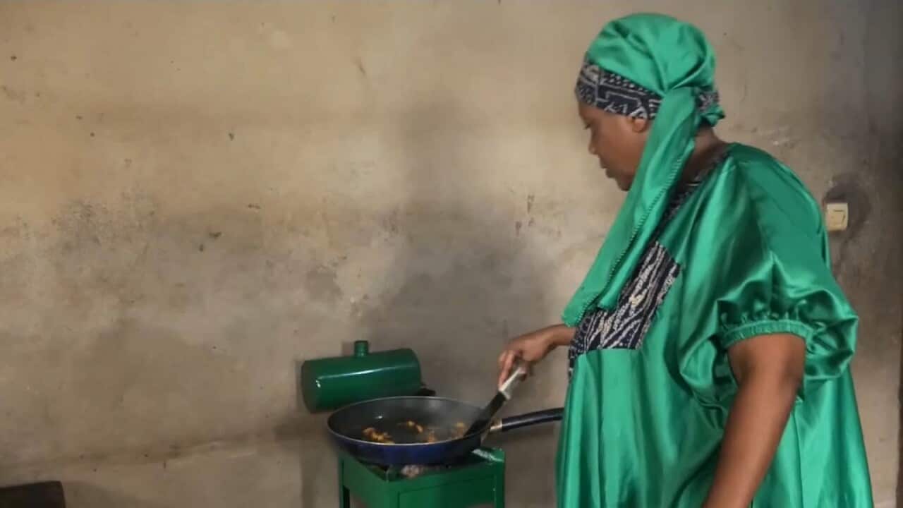 Suzanne Noubissie cooks with her recycled car oil stove (AP).jpg