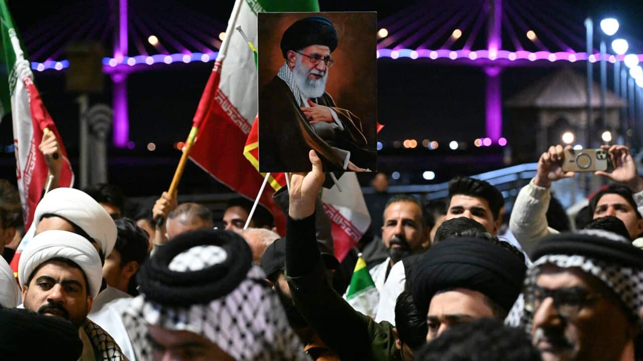 A group of protesters carrying Iranian, Iraqi and Hezbollah flags as well as portraits of Iran's supreme leader Ayatollah Ali Khamenei