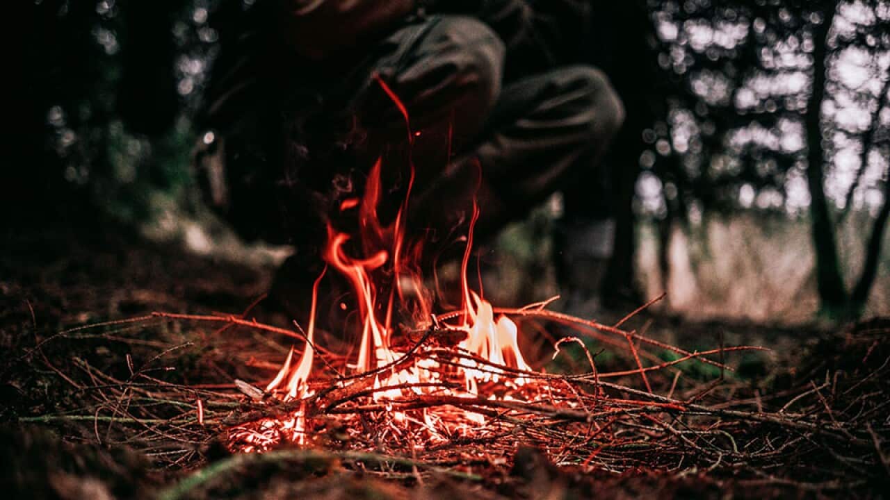 Image of a dried twigs burning with a person in the background