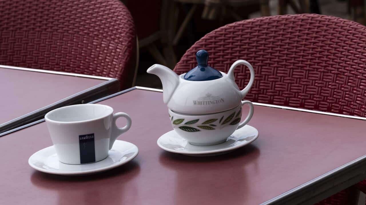 France, Europe, Tea cup and teapot with a coffee cup on a cafe table outside.