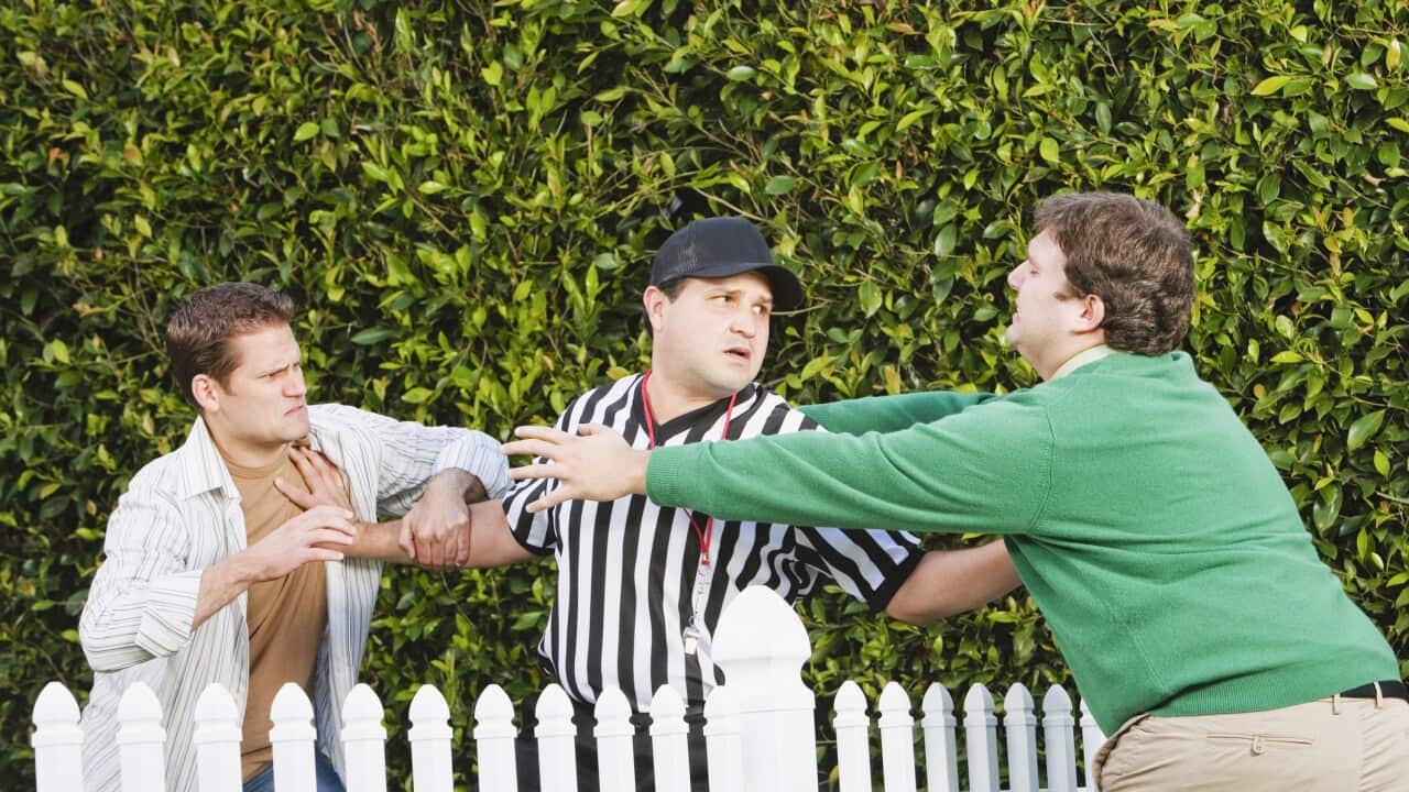 Hispanic referee between arguing neighbors