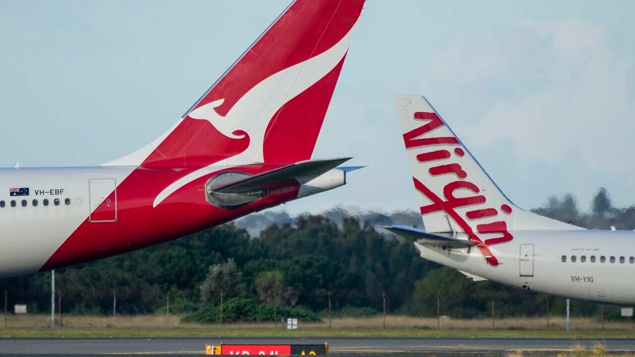 A Qantas and a Virgin plane facing opposite ends to each other on an airport tarmac.