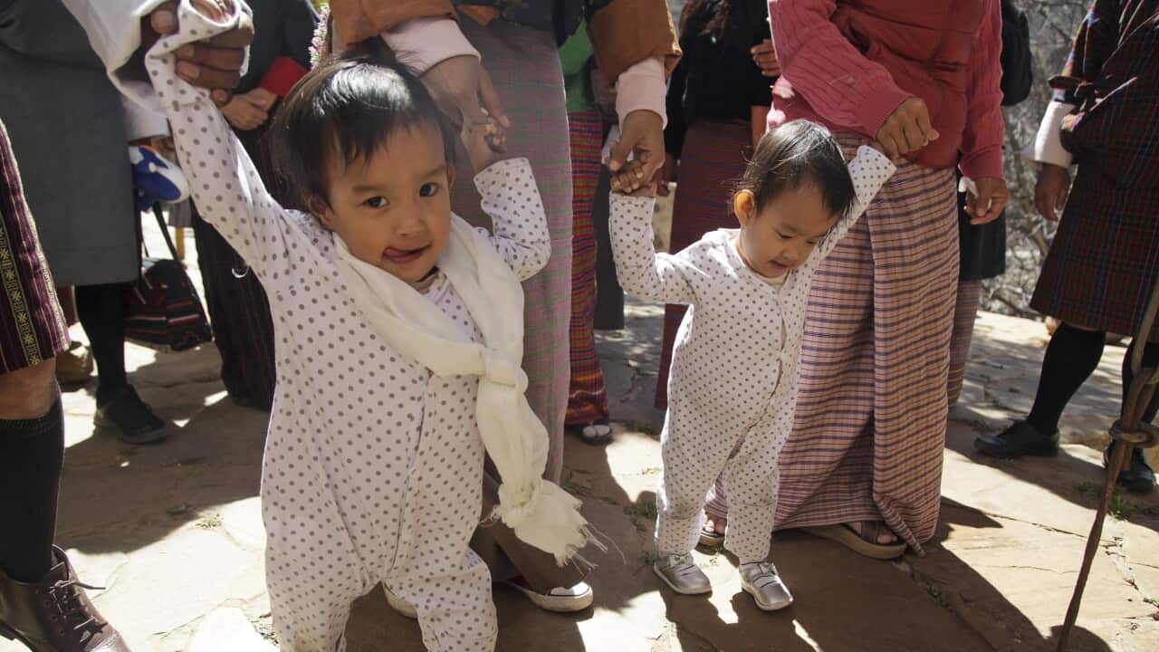 Conjoined Bhutanese twin sisters Nima and Dawa walk with family members at the Tachog Lhakhang Buddhist temple on the outskirts of Thimphu, Bhutan.