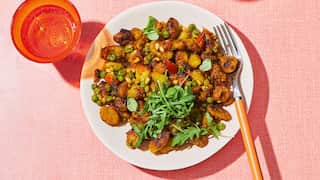 Seen from overhead, two plates with golden gnocchi sit on a blush-coloured tablecloth. Orange glasses sit alongside.
