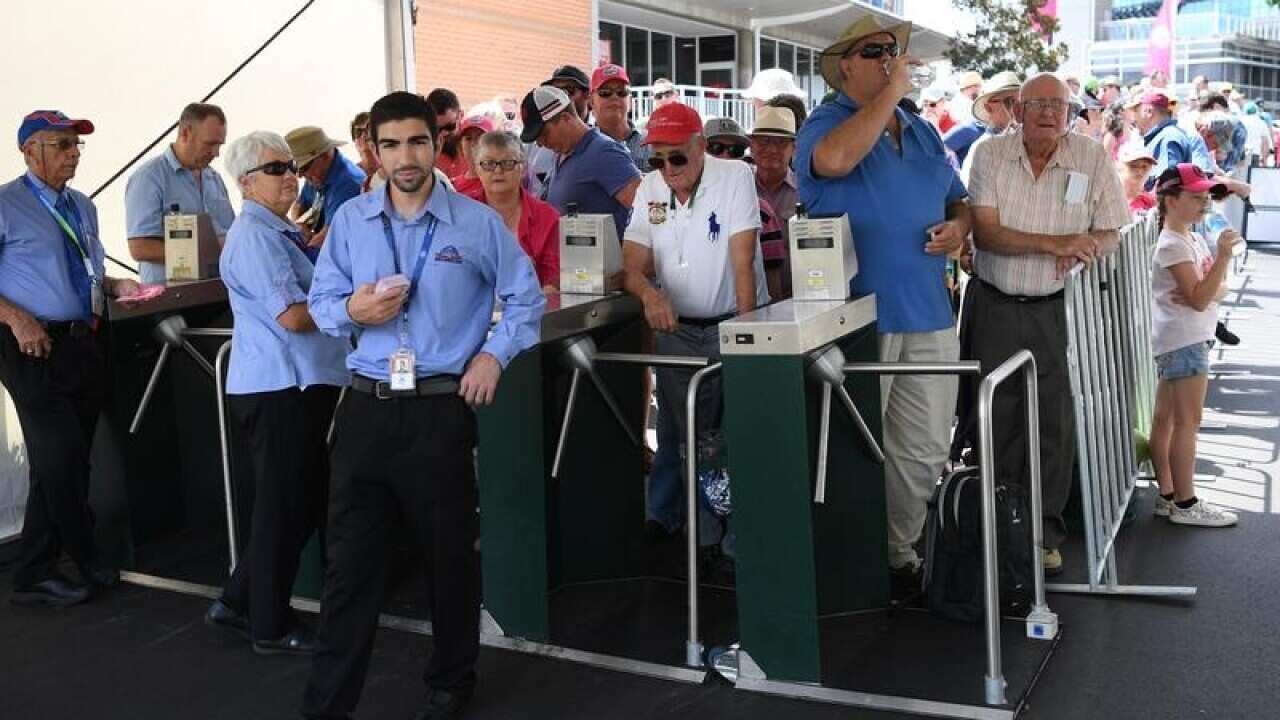 Crowds of people wait for a delayed entry into the stadium.