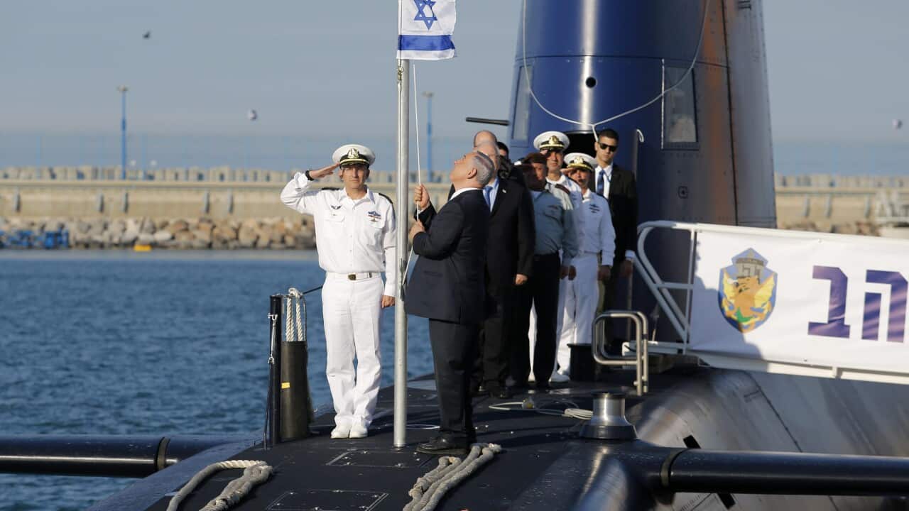 Israeli Prime Minister Benjamin Netanyahu (C) raises the Israeli flag on the new submarine 'Rahav'. The vessel is said to be capable of firing nuclear warheads