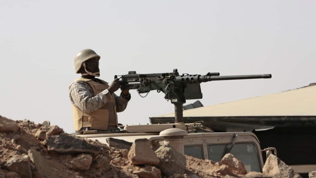 A Saudi soldier sits on top of an armor vehicle as he aims his weapons, on the border with Yemen, at a military point in Najran, Saudi Arabia
