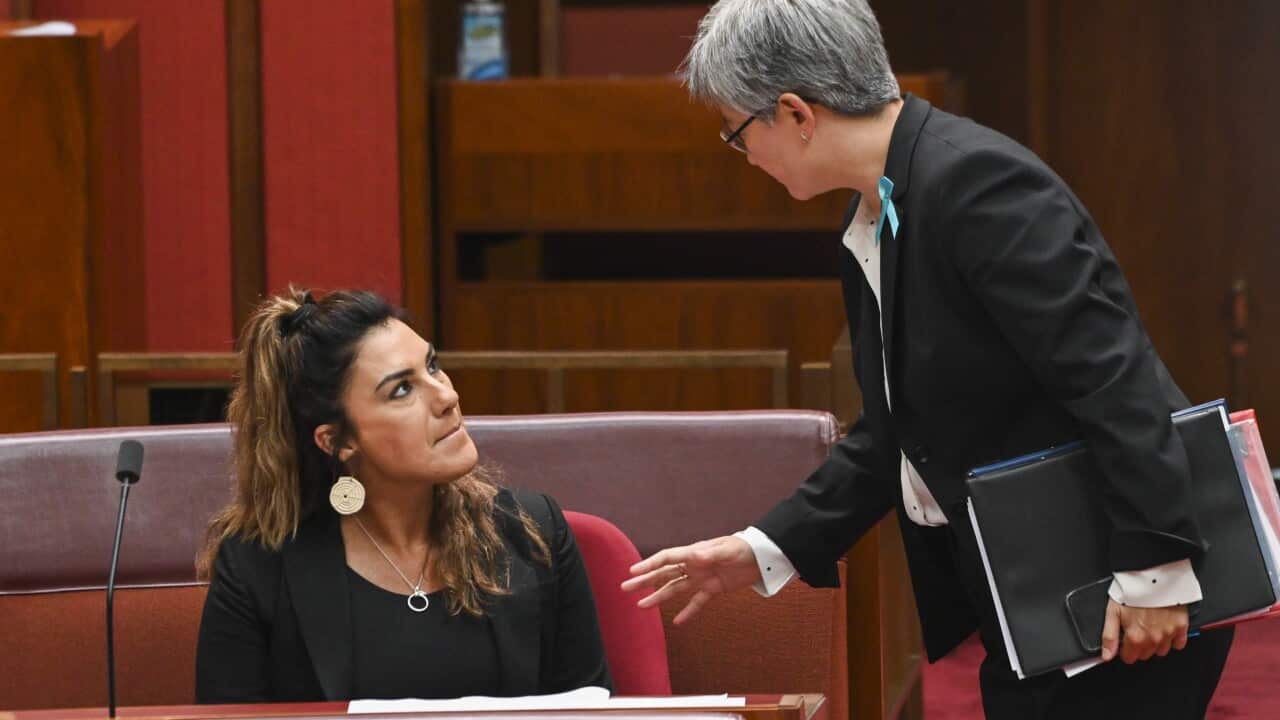 Two women are having a conversation, one sitting and the other standing.