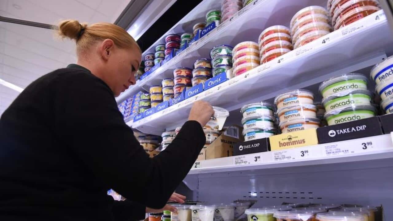 An employee stocking up a supermarket fridge