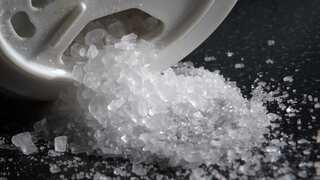 A close-up photo shows sea salt being poured from a salt shaker.