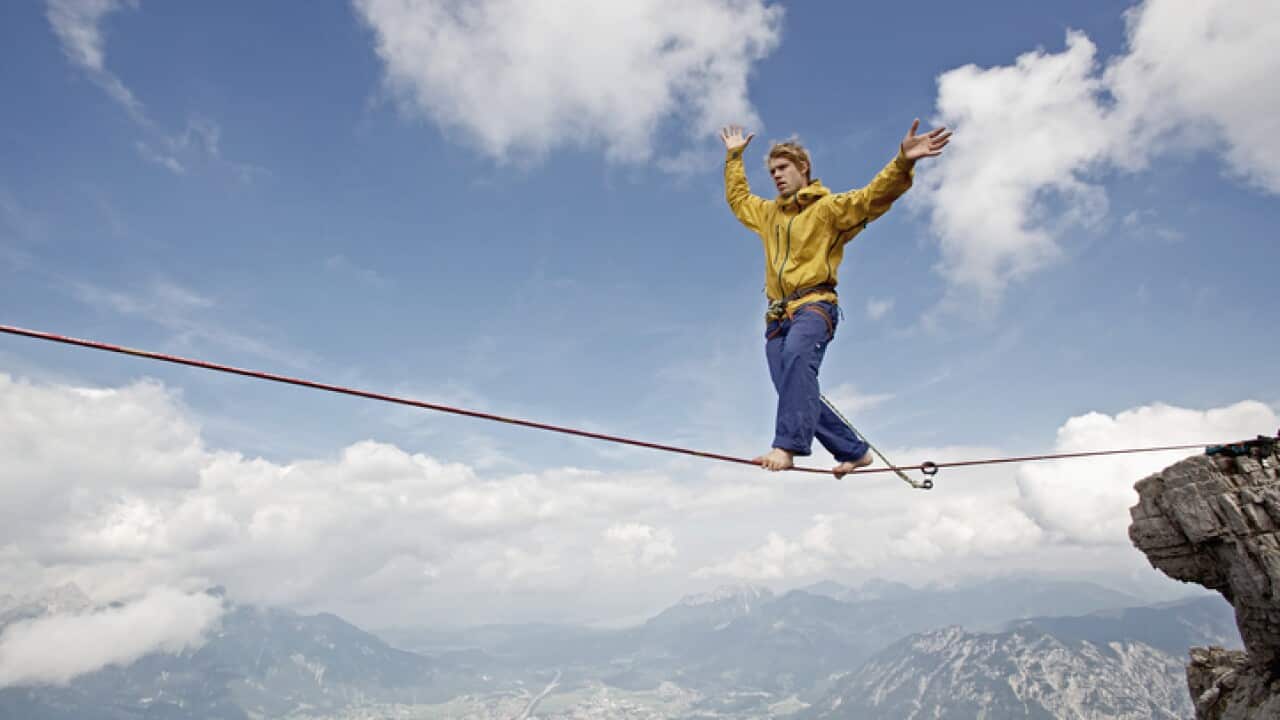 Young man balancing on high rope between two rocks in mountains, Alps, Tyrol, Austria