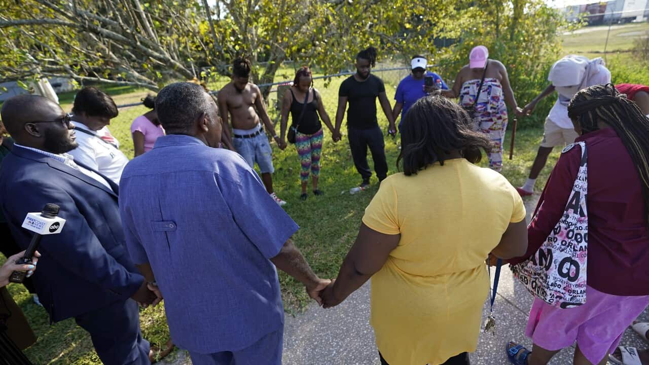 People gather around in a circle holding hands.