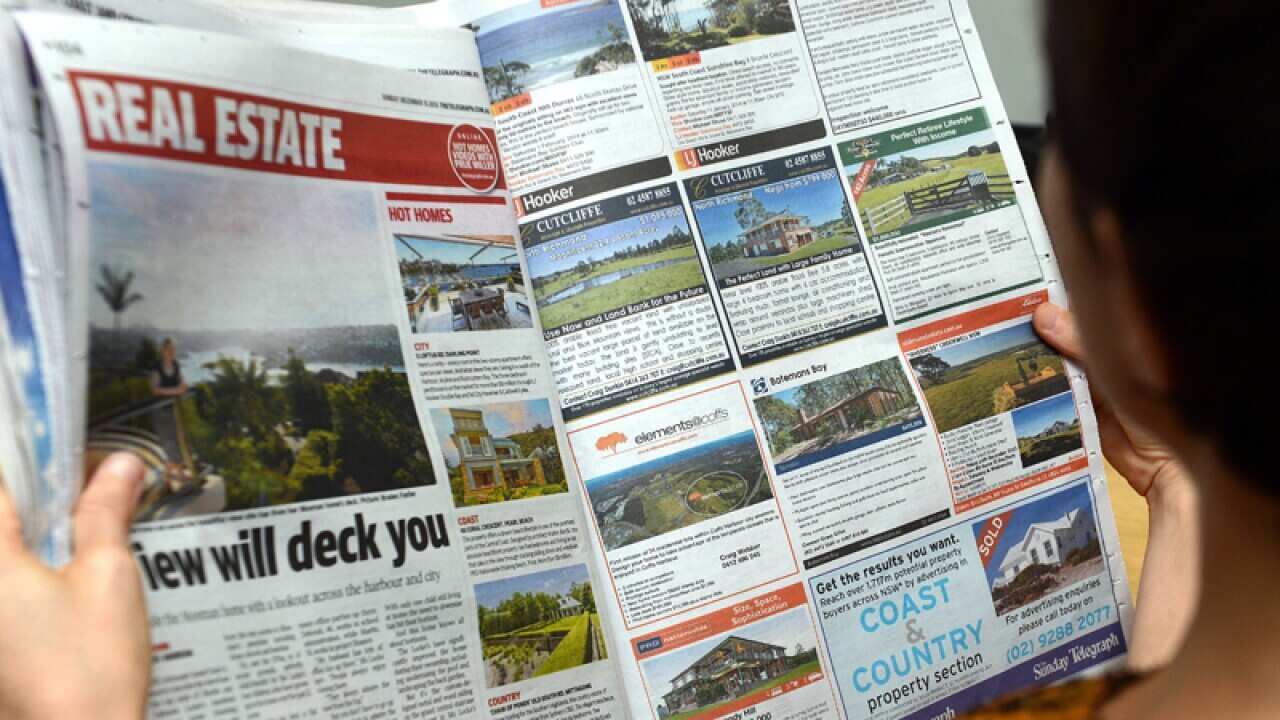 A woman looks at real estate advertising in a newspaper