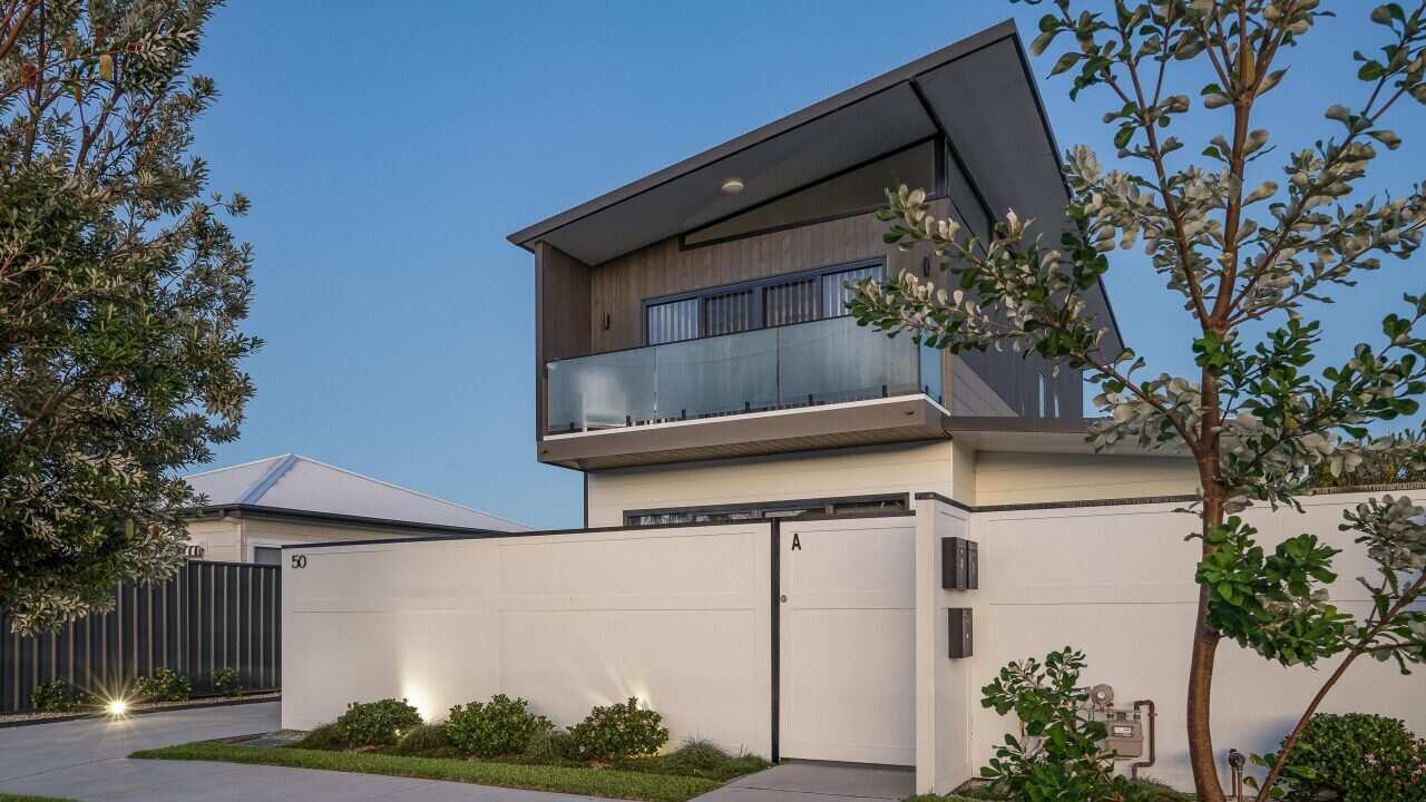 A two-story home with a white fence built around it.