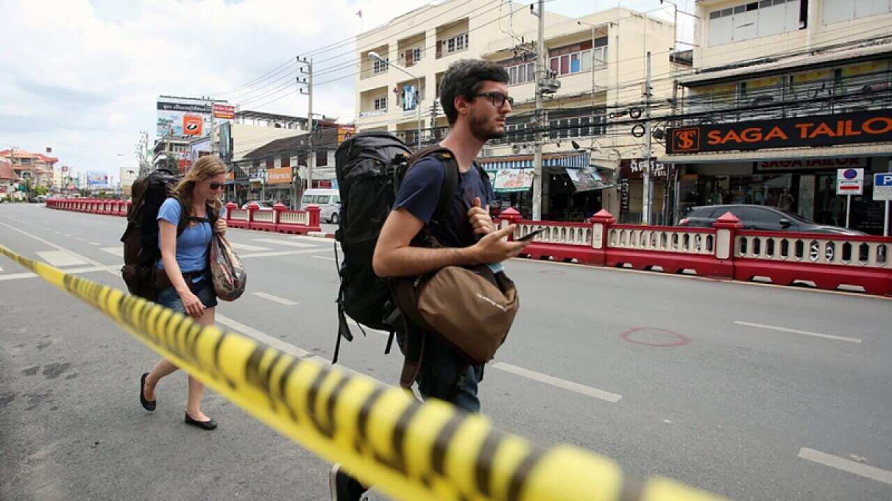 Tourists walk past police line at the bomb blast site in Hua Hin